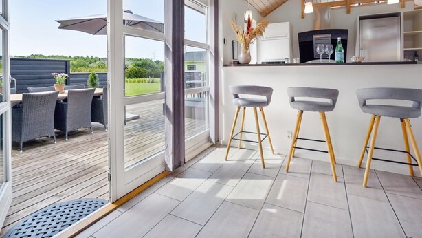 Una cocina moderna con barra, ventanas amplias y una terraza.