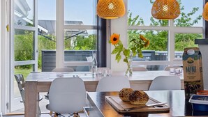 Un comedor moderno con una mesa, sillas y vistas a la vegetación exterior.