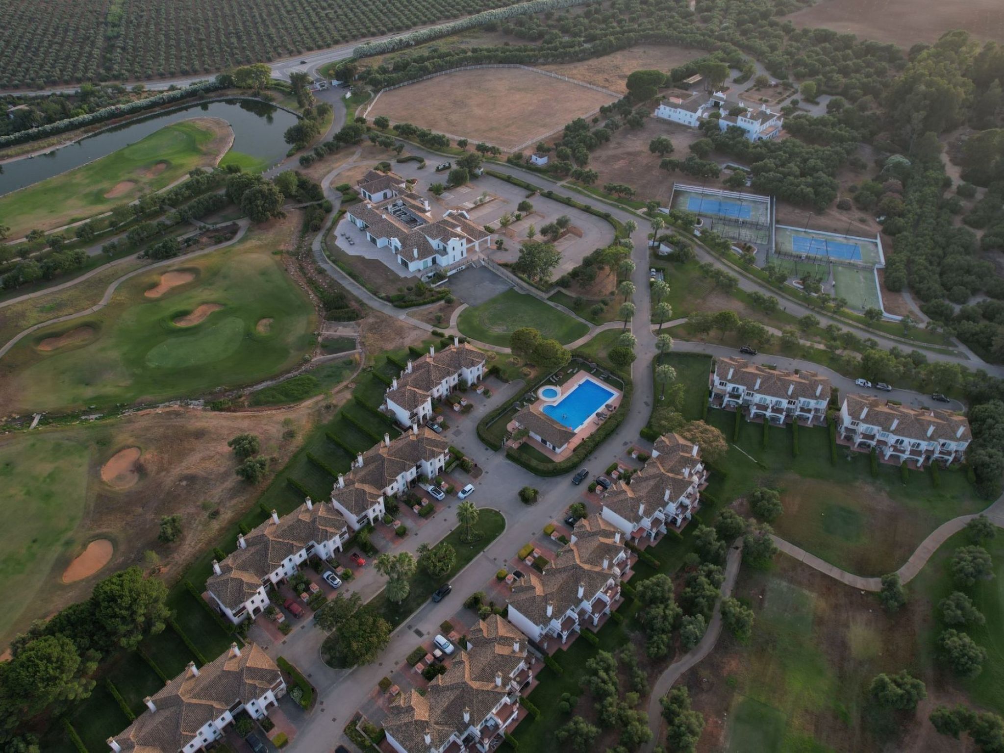 Luchtbeeld van een woonwijk met huizen, een zwembad en een golfbaan.