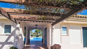 A covered outdoor area with a pool, potted plants, and a pergola. - Arcos Gardens Golf by Interhome (Arcos de la Frontera)