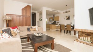 A modern living room with a sofa, coffee table, and a dining area with chairs and a table. - Arcos Gardens Golf by Interhome (Arcos de la Frontera)