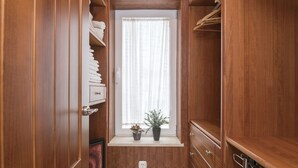 A narrow walk-in closet with wooden doors, a window with sheer curtains, and a potted plant on the windowsill. - Arcos Gardens Golf by Interhome (Arcos de la Frontera)