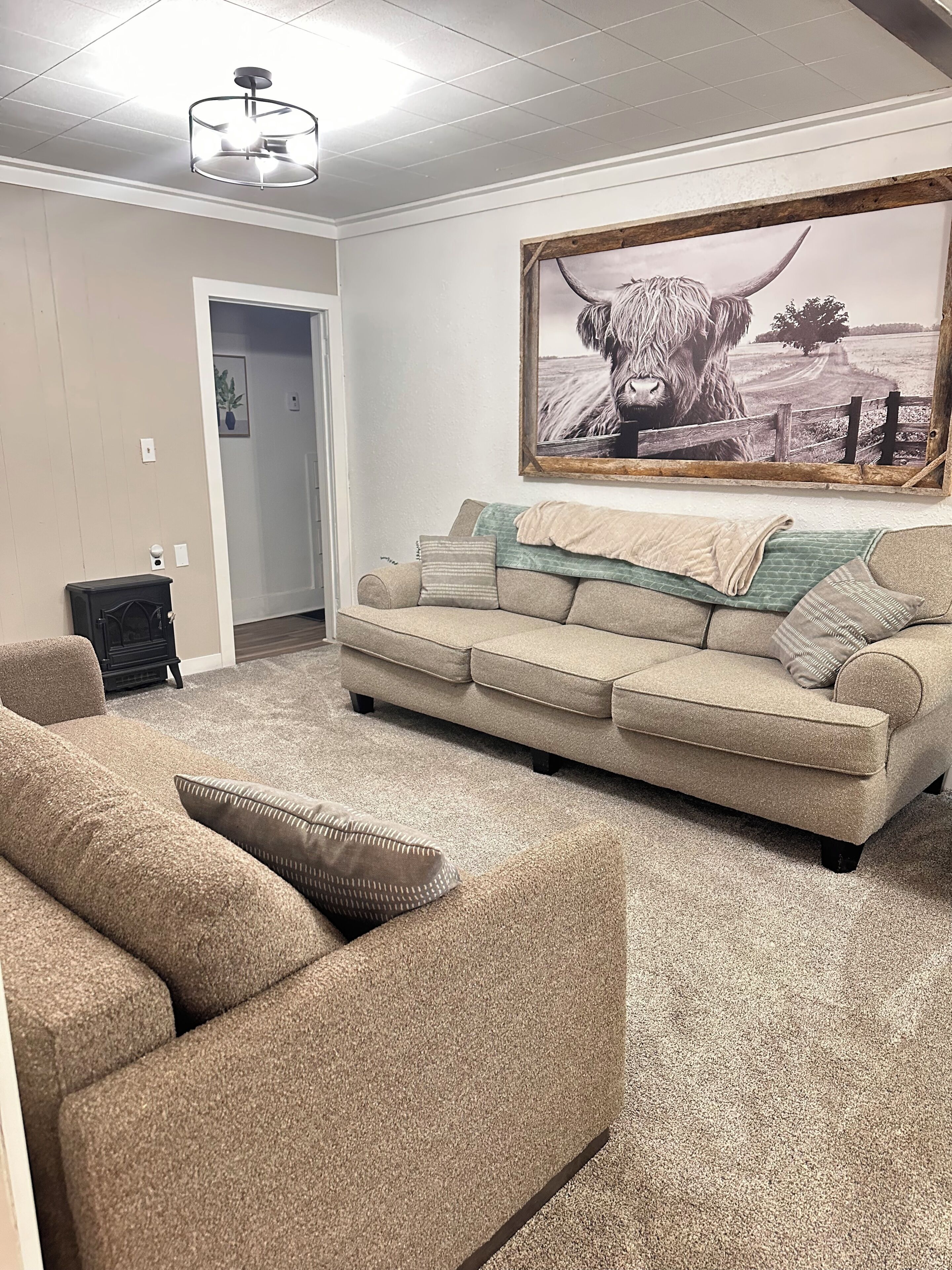A living room with a beige sofa, a fireplace, and a large framed picture of a bull.