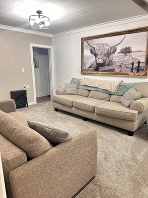 A living room with a beige sofa, a fireplace, and a large framed picture of a bull.