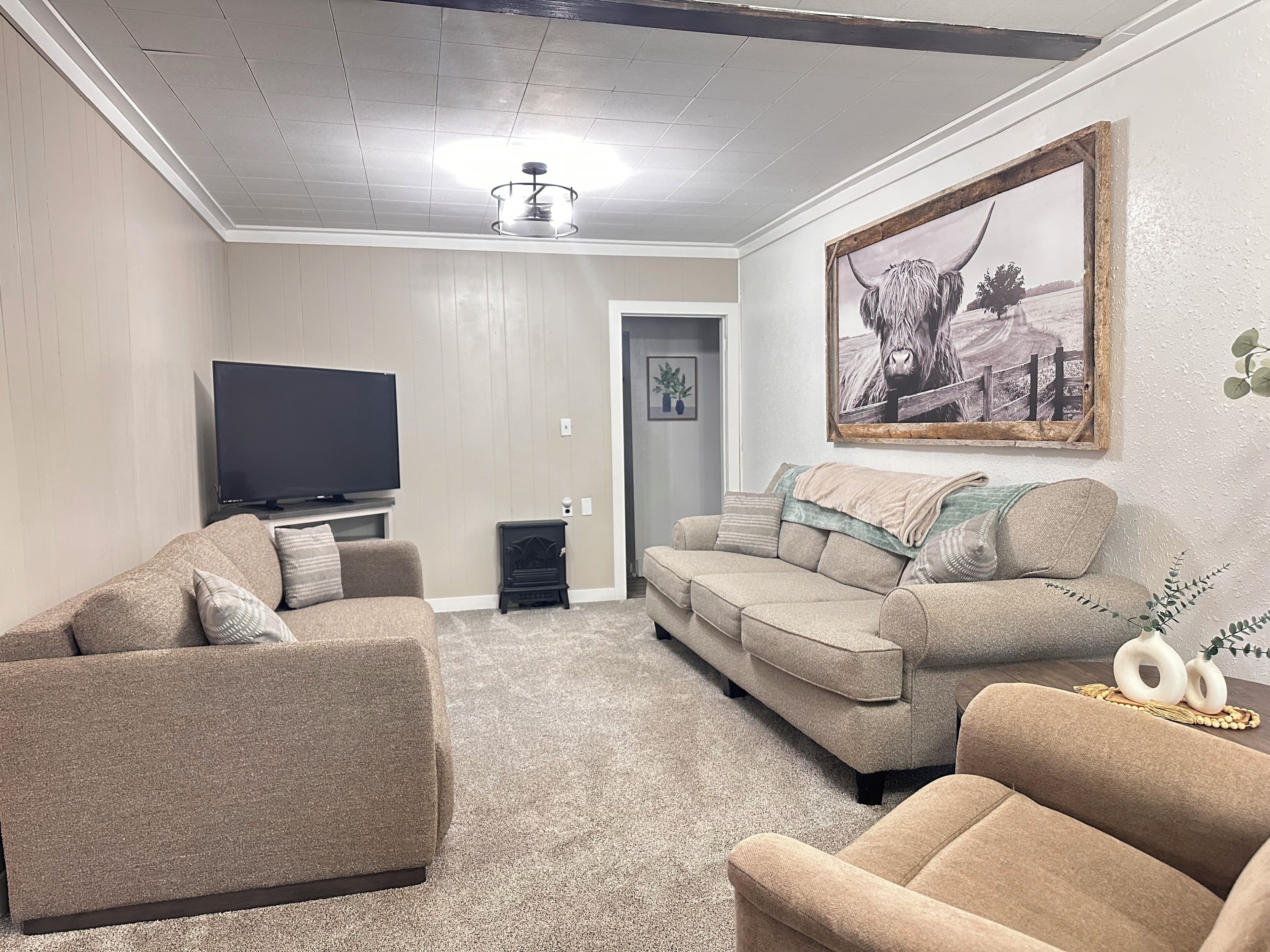 A living room with a flat-screen TV, two sofas, a fireplace, and a large painting on the wall.