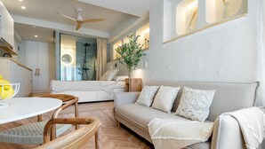 Een moderne woonkamer met een bank, stoelen, een eettafel en een plafondventilator.