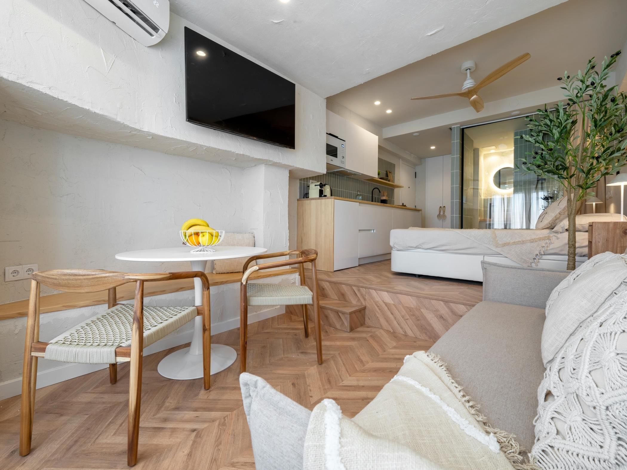 A compact living space with a dining area, kitchenette, and a sofa.