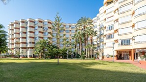 Een meerlaags hotel met een centrale binnentuin, met palmbomen en een verzorgd gazon.