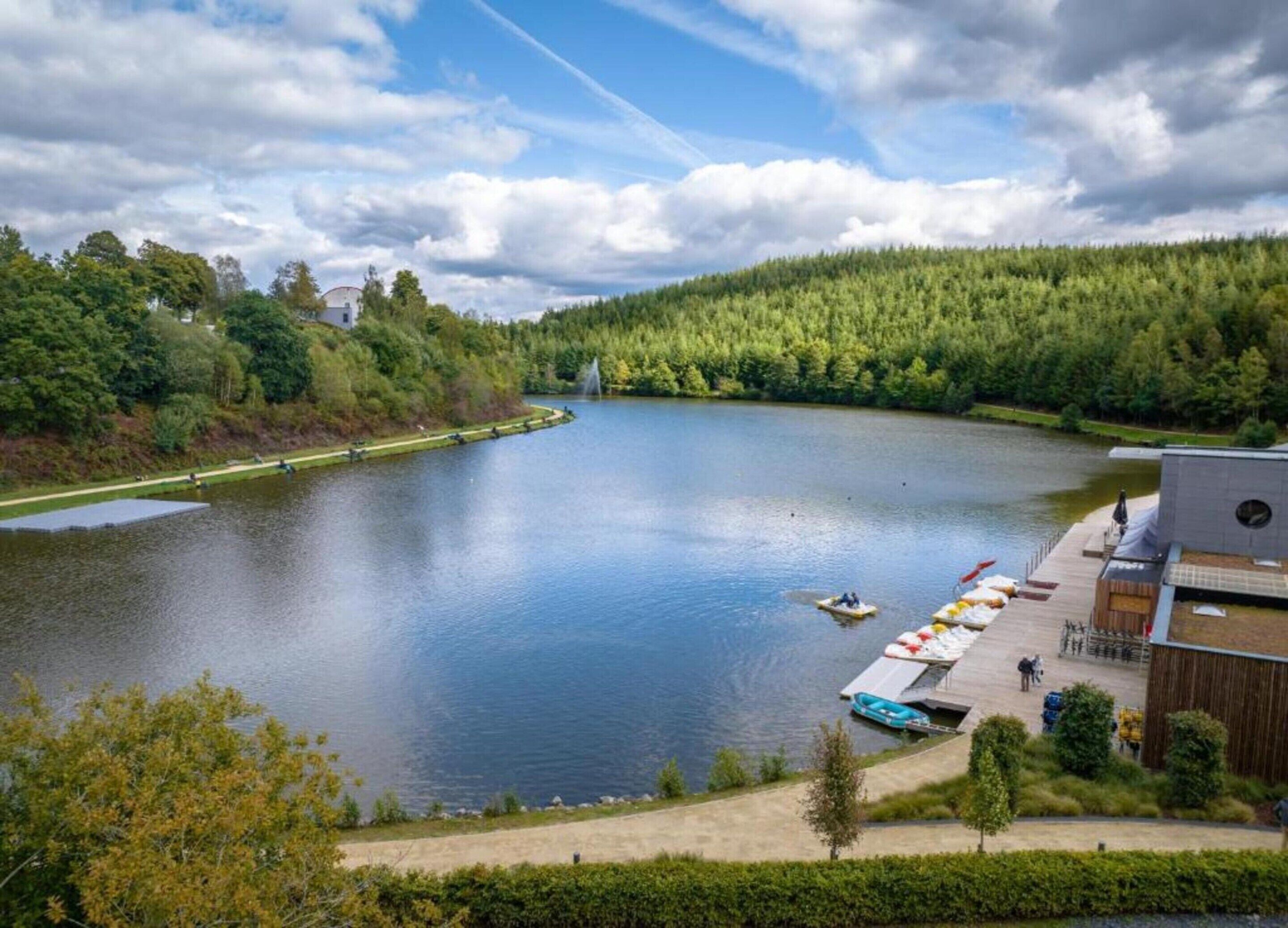A lake with boats, a dock, and a building with a modern design.