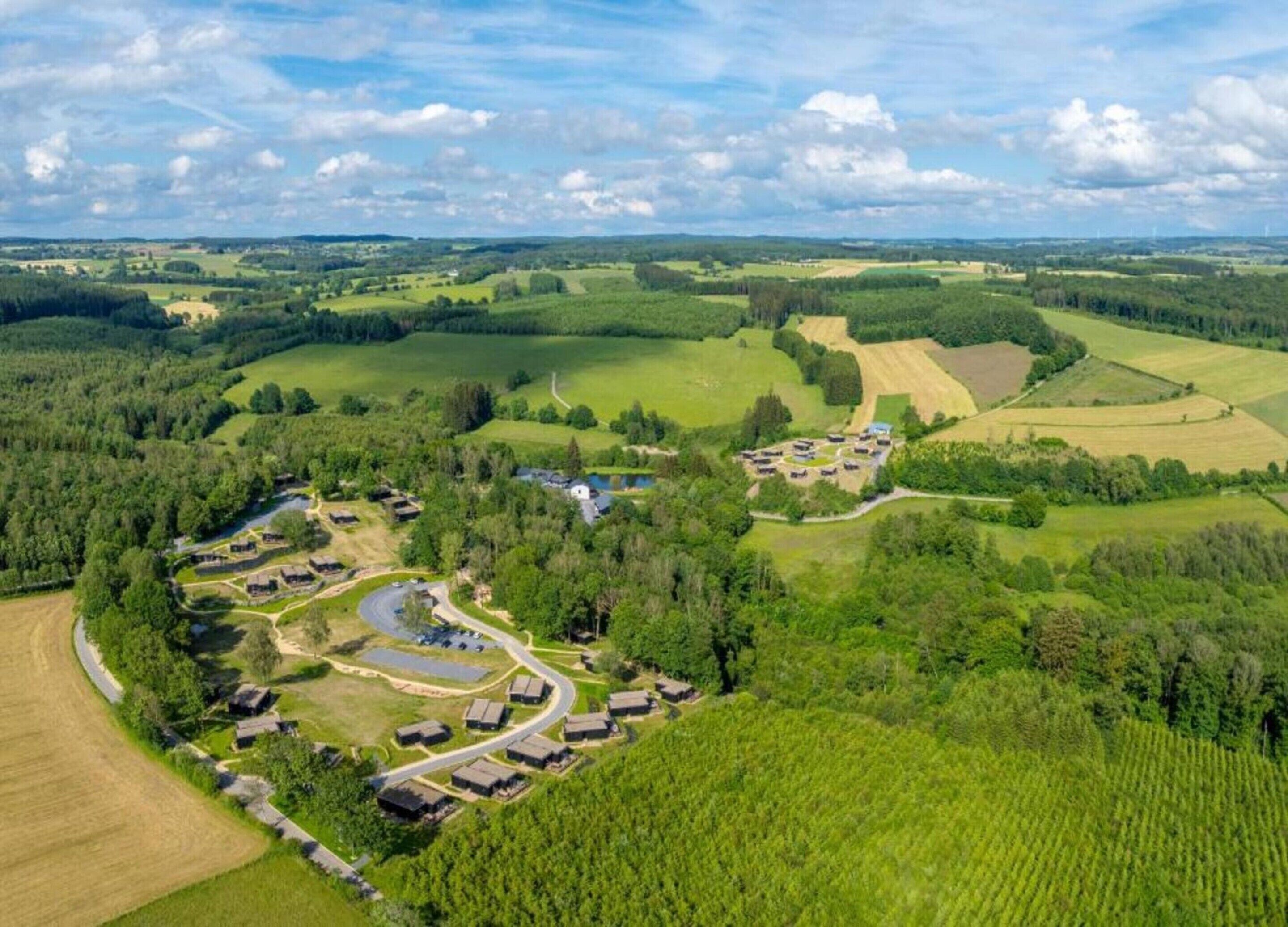 Luchtbeeld van een landelijk gebied met een groep gebouwen, omringd door velden en bossen.