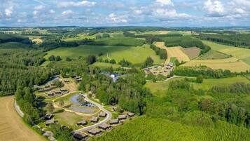 Luchtbeeld van een landelijk gebied met een groep gebouwen, omringd door velden en bossen.