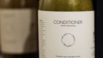 Een fles conditioner met een etiket waarop een cirkeldiagram en tekst staan over natuurbescherming en afvalvrij leven.
