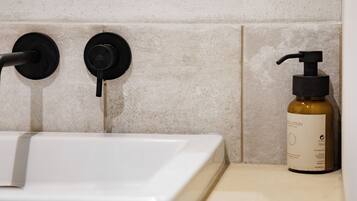 A bathroom with a white sink, black faucet, and a bottle of body lotion on the counter.