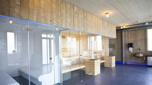 A modern spa room with glass partitions, wooden benches, and a blue-lit floor. - Villa With Roof Terrace Near Veluwemeer (Nijkerk)