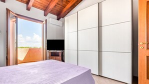 A bedroom with a bed, a sliding door, a TV, and a view of the outdoors. - GuestHost - Sweet Home in Portoscuso! (Portoscuso)