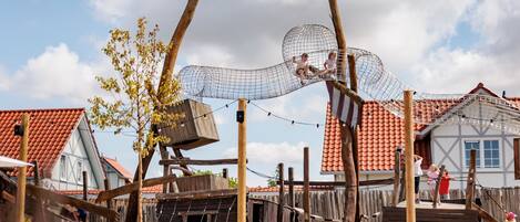 A rustic outdoor play area with wooden structures and rope bridges.