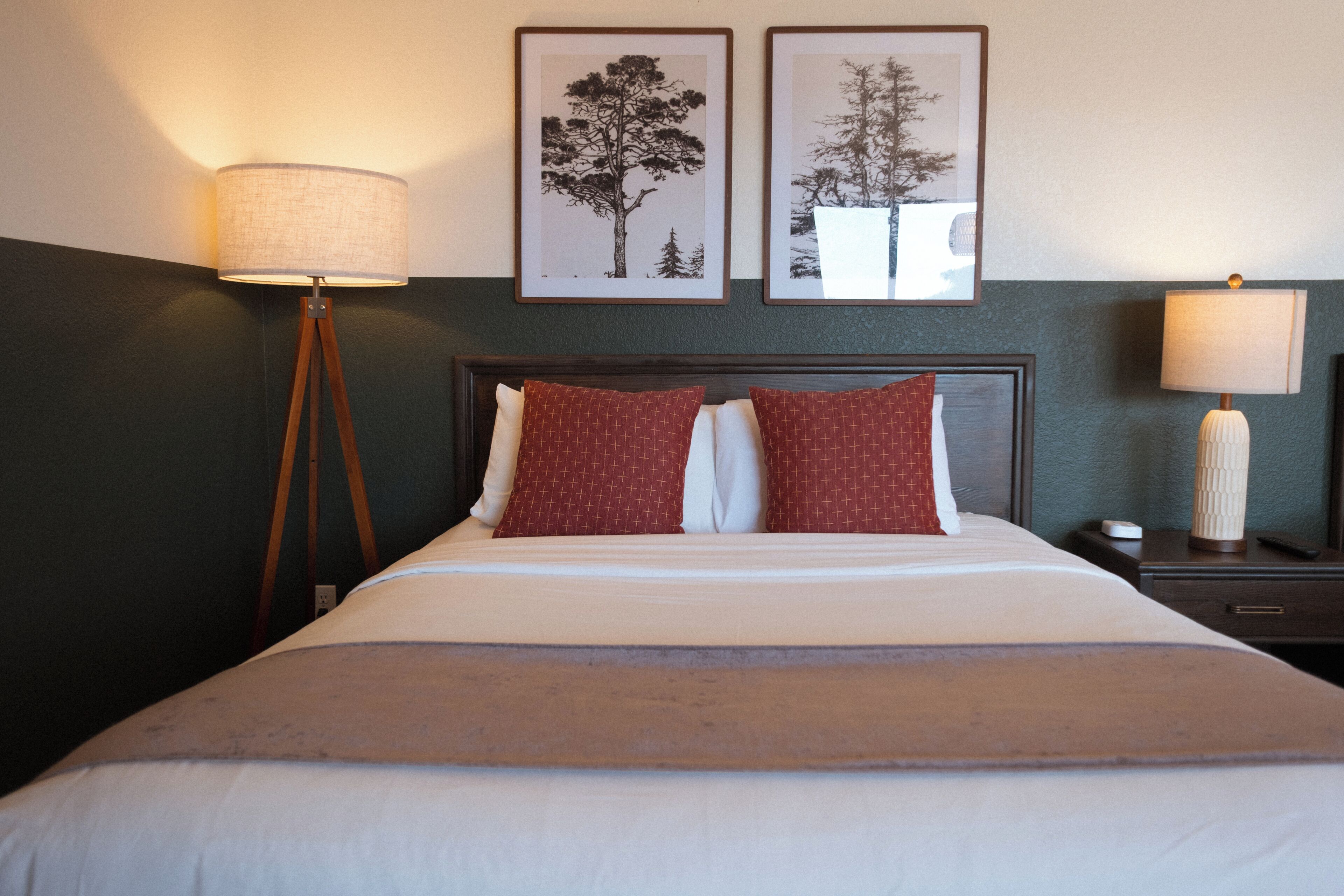 A neatly made bed with a wooden headboard, two bedside tables, and a floor lamp.