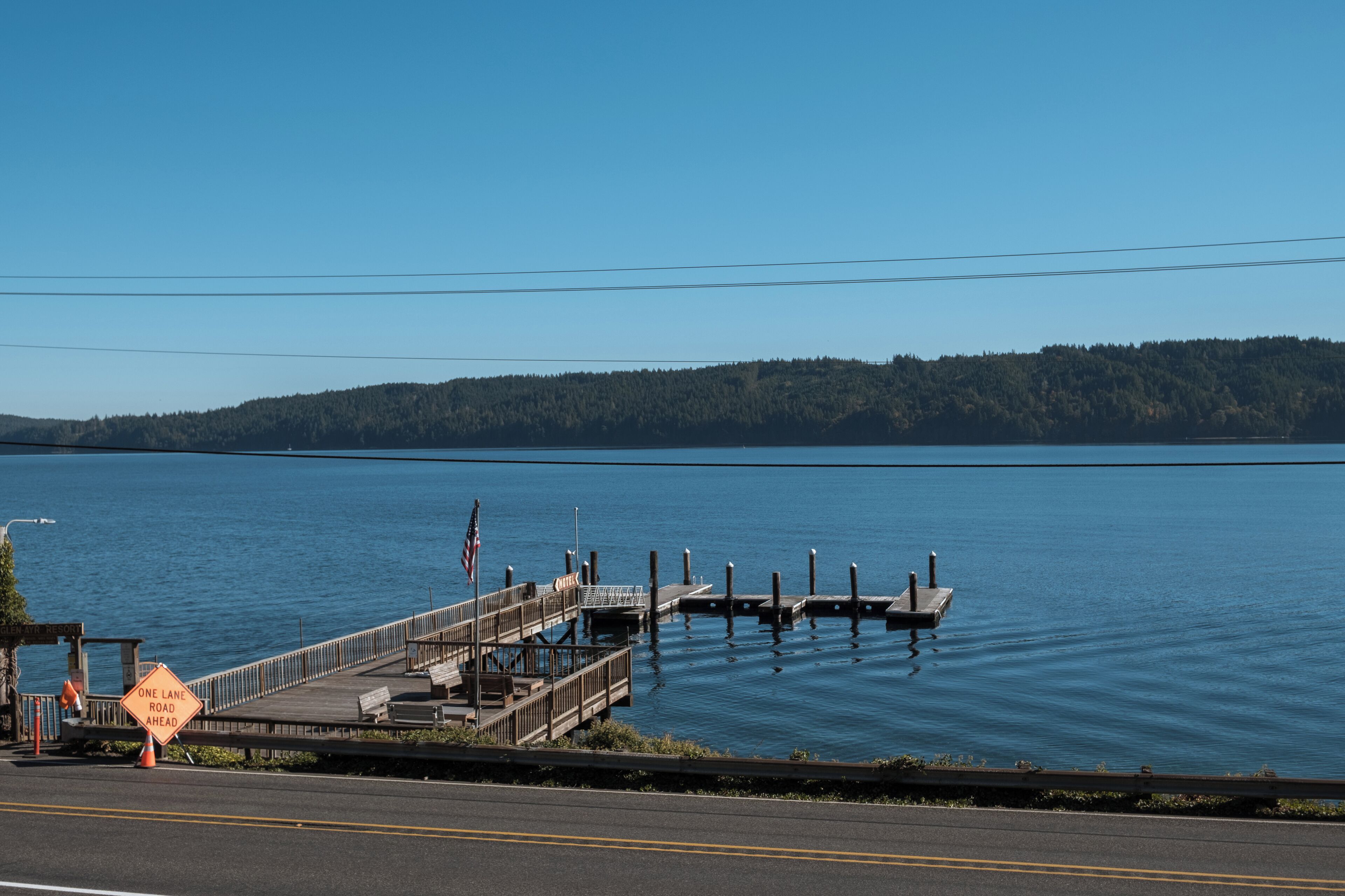 A pier extending into a calm lake with a clear sky.