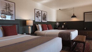 Een hotelkamer met twee bedden, een bankje, een bureau en een spiegel.