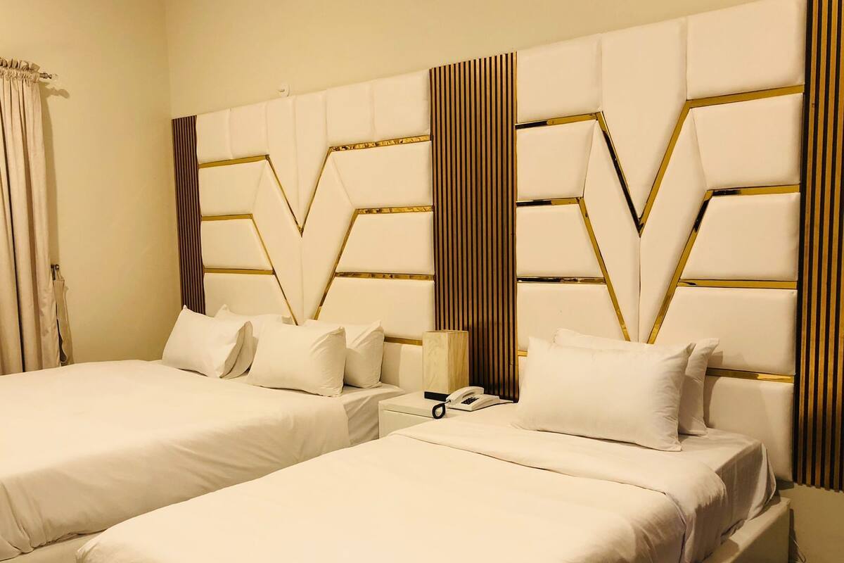 A hotel room with two beds, a nightstand, and a telephone.