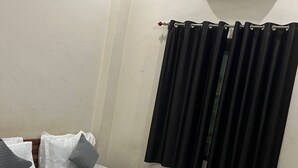 Een hotelkamer met een bed, een gordijn en een airco aan de muur.