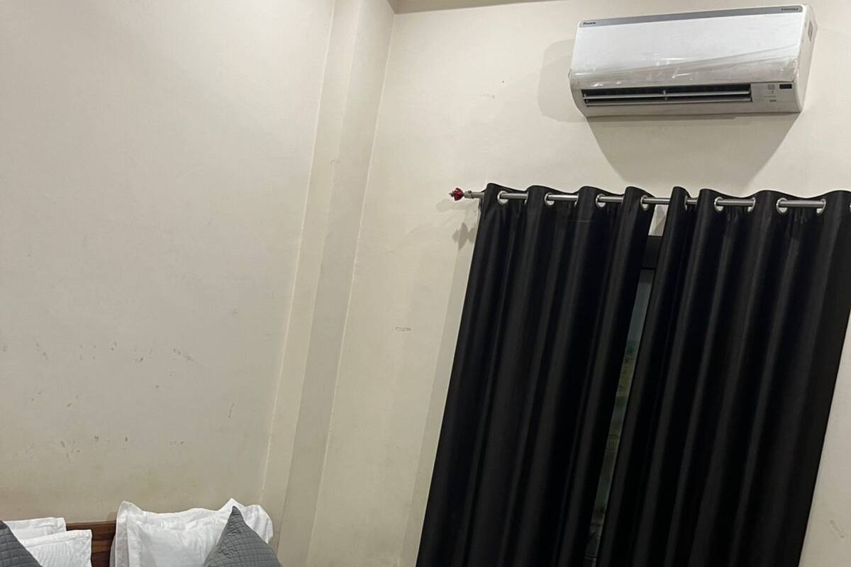 Une chambre d’hôtel avec un lit, un rideau et un appareil de climatisation fixé au mur.