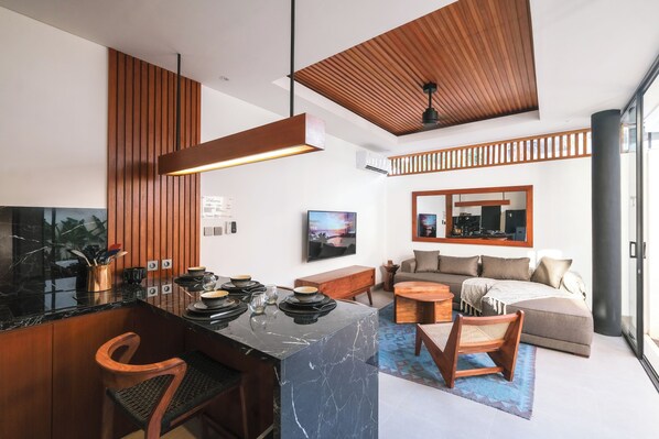 Una cocina moderna con encimera de mármol, detalles de madera y un comedor con mesa y sillas redondas.