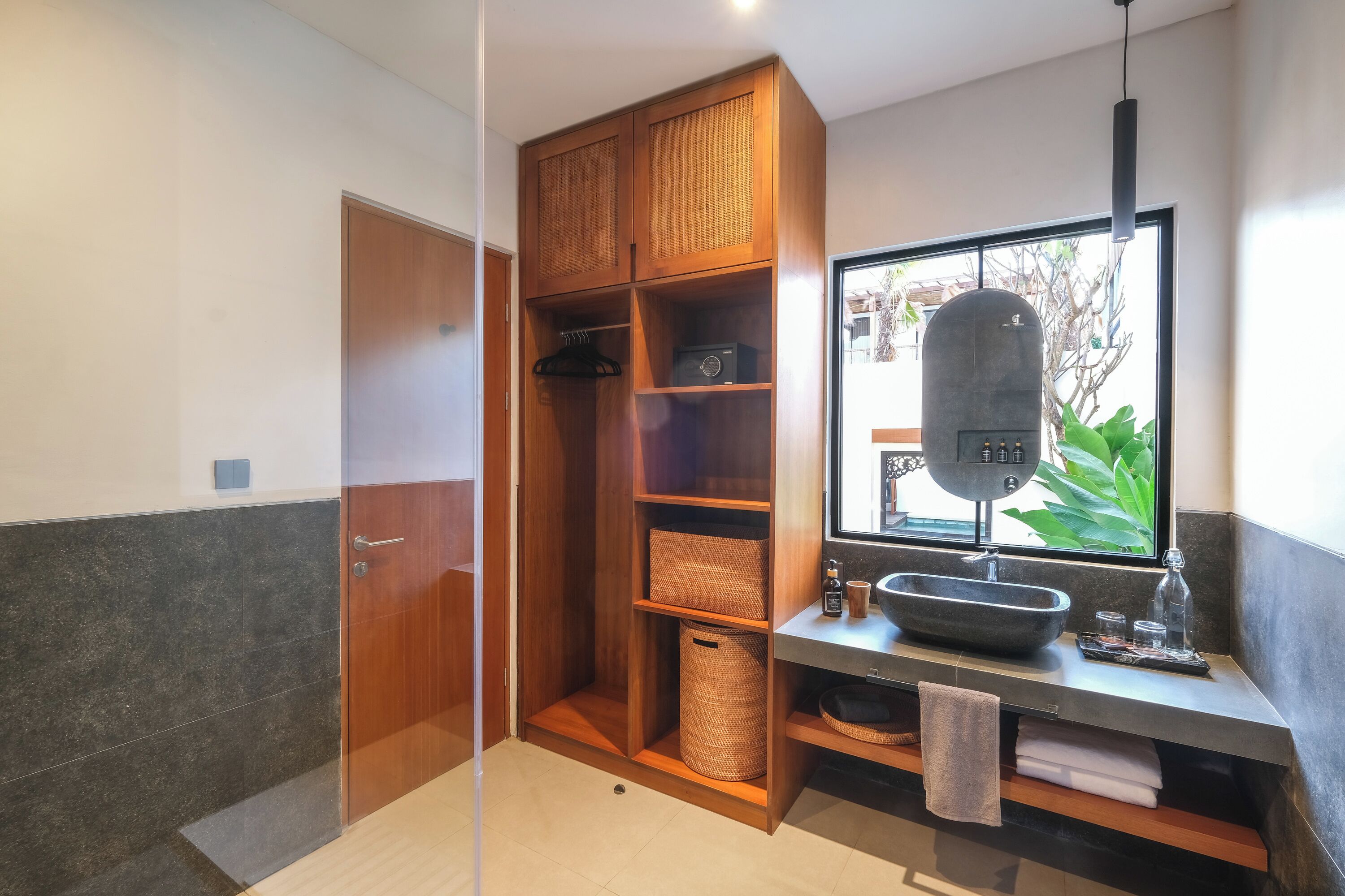 A modern bathroom with a wooden vanity, a large window, and a built-in shower area.