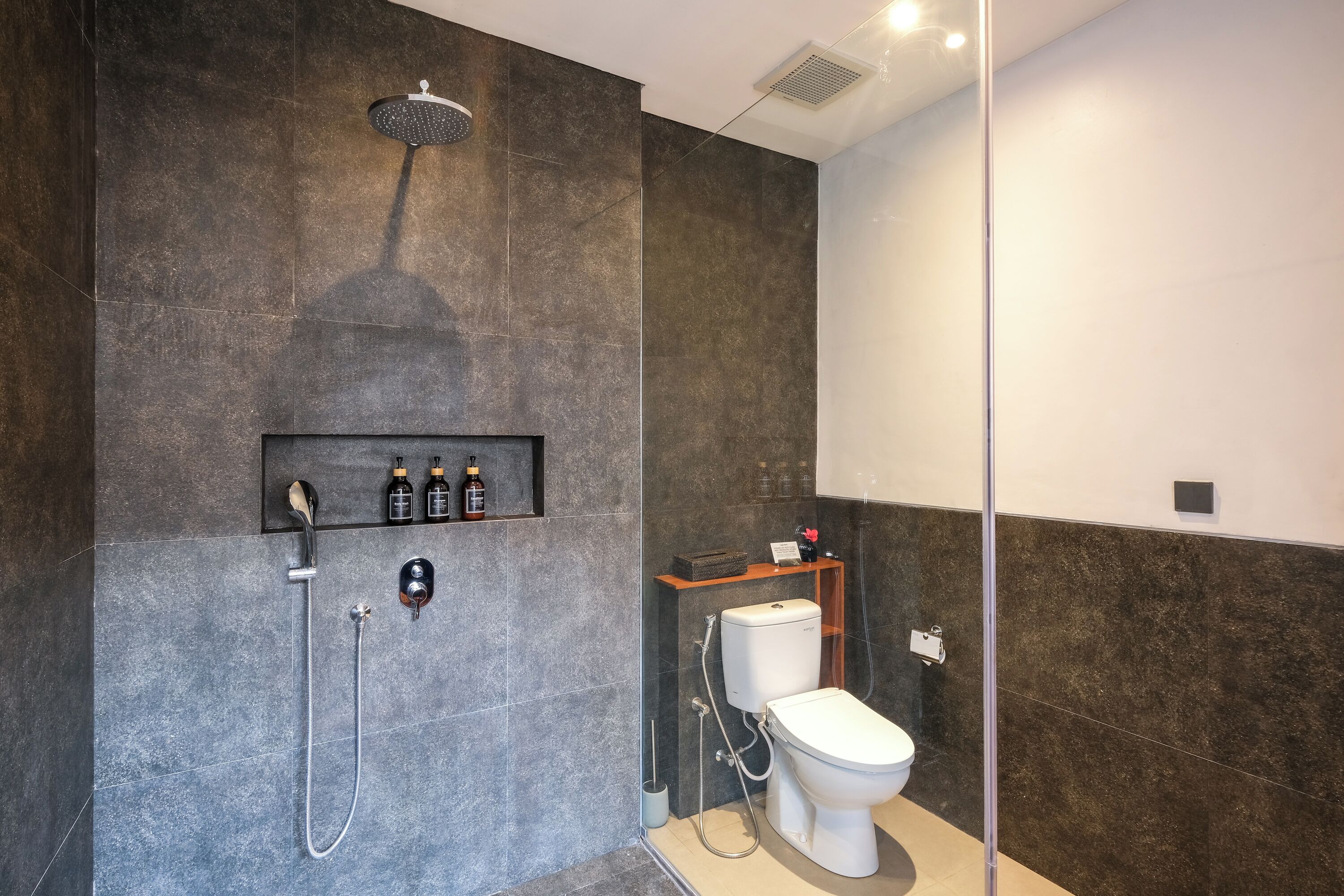 Une salle de bain moderne équipée d’une douche, de toilettes et d’une étagère de rangement.