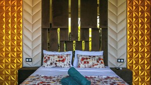 A modern bedroom with a geometric patterned wall, a large bed with two pillows, and a nightstand. - Jnane Riad (Ghmate)