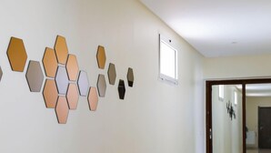A hallway with a series of hexagonal wall decorations and a sliding glass door leading to another room. - Jnane Riad (Ghmate)
