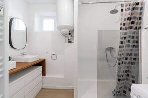 Un baño moderno con lavamanos blanco, espejo y zona de ducha.