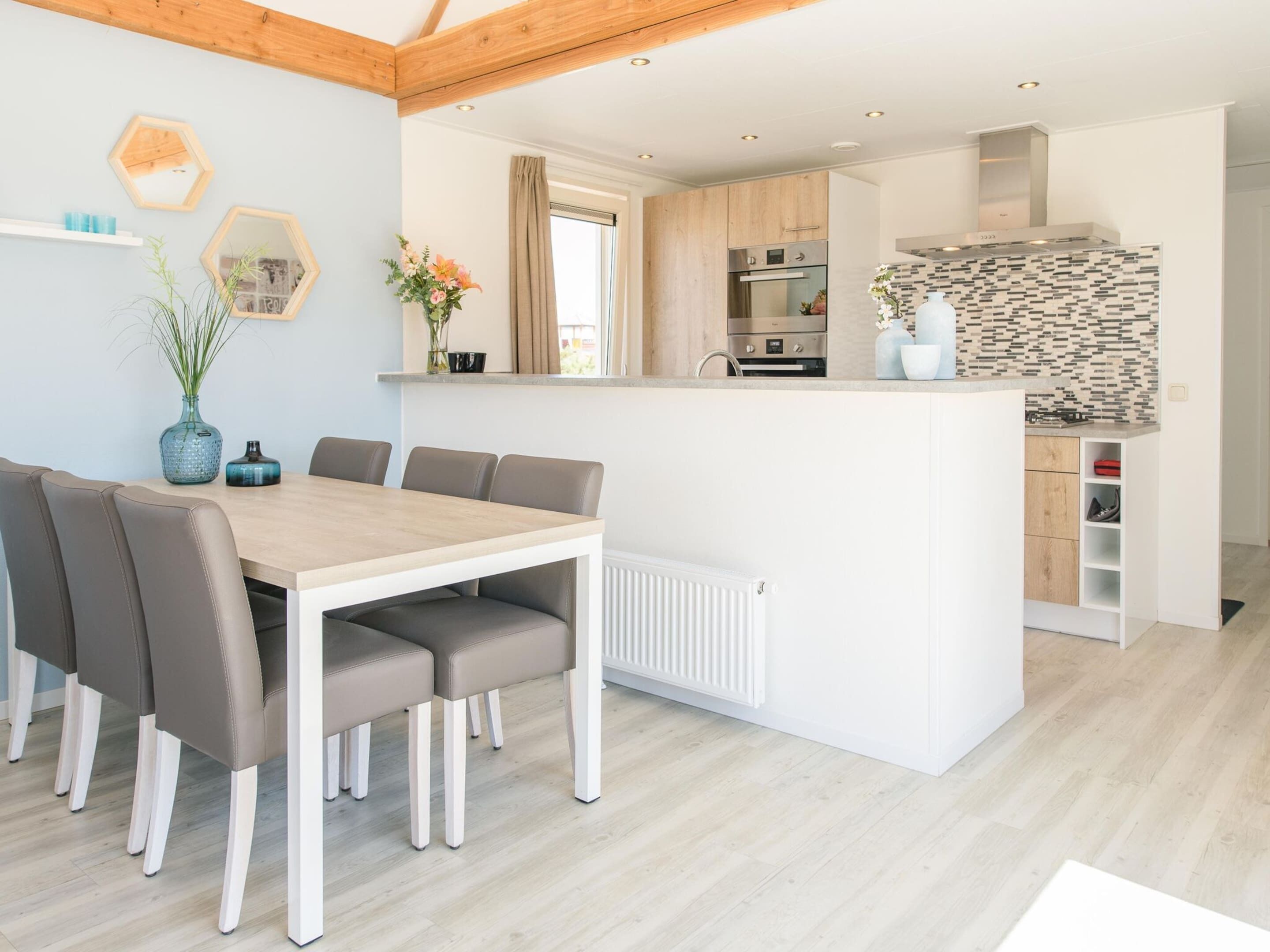 A modern kitchen with wooden cabinets, a built-in oven, and a backsplash with a geometric pattern.