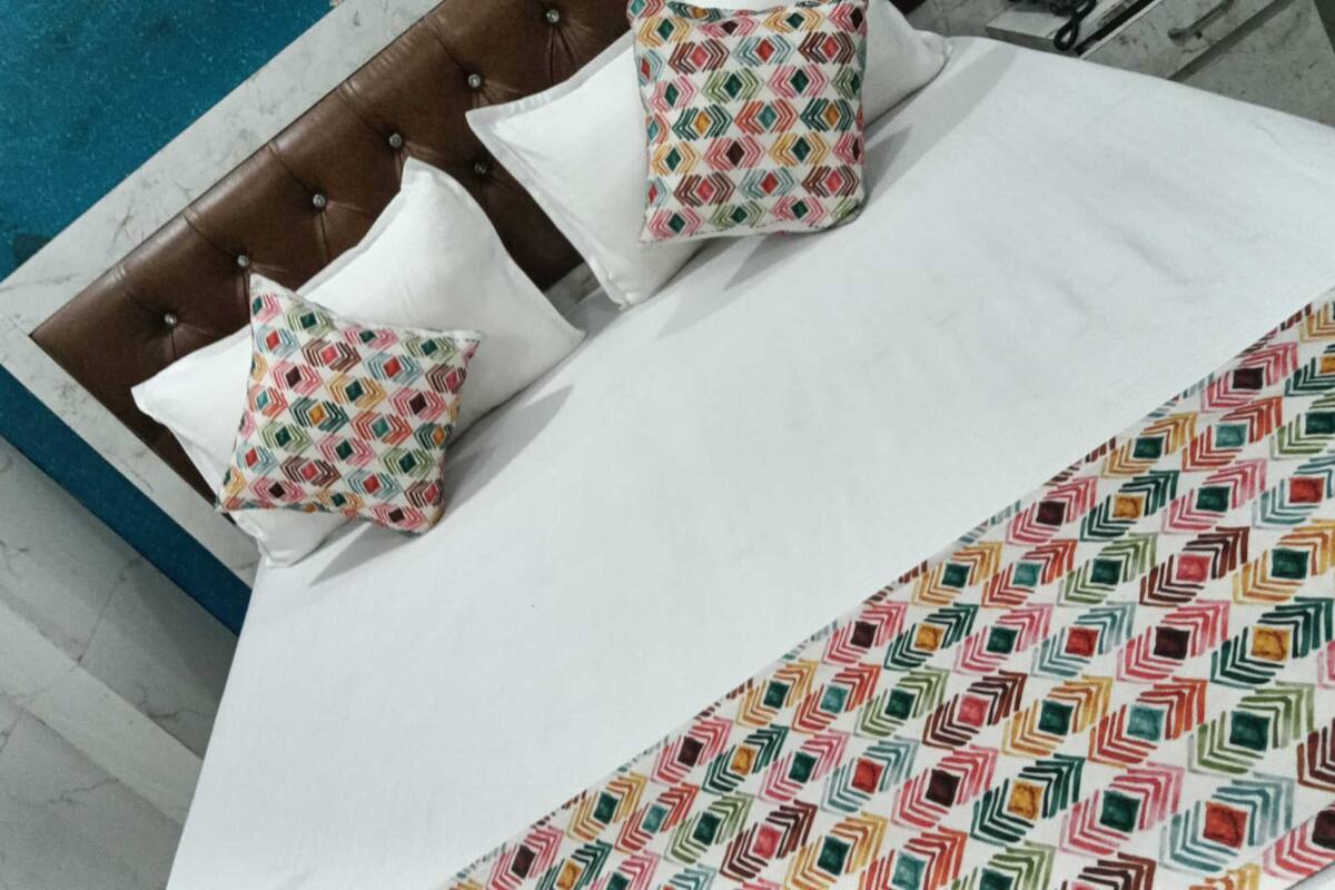 Een bed met een bedspreide met een patroon en twee kussens met een geometrisch ontwerp.