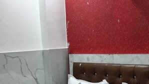A hotel room with a bed, pillows, and a marble wall. - Hotel Kanak Palace By GRB (New Delhi)
