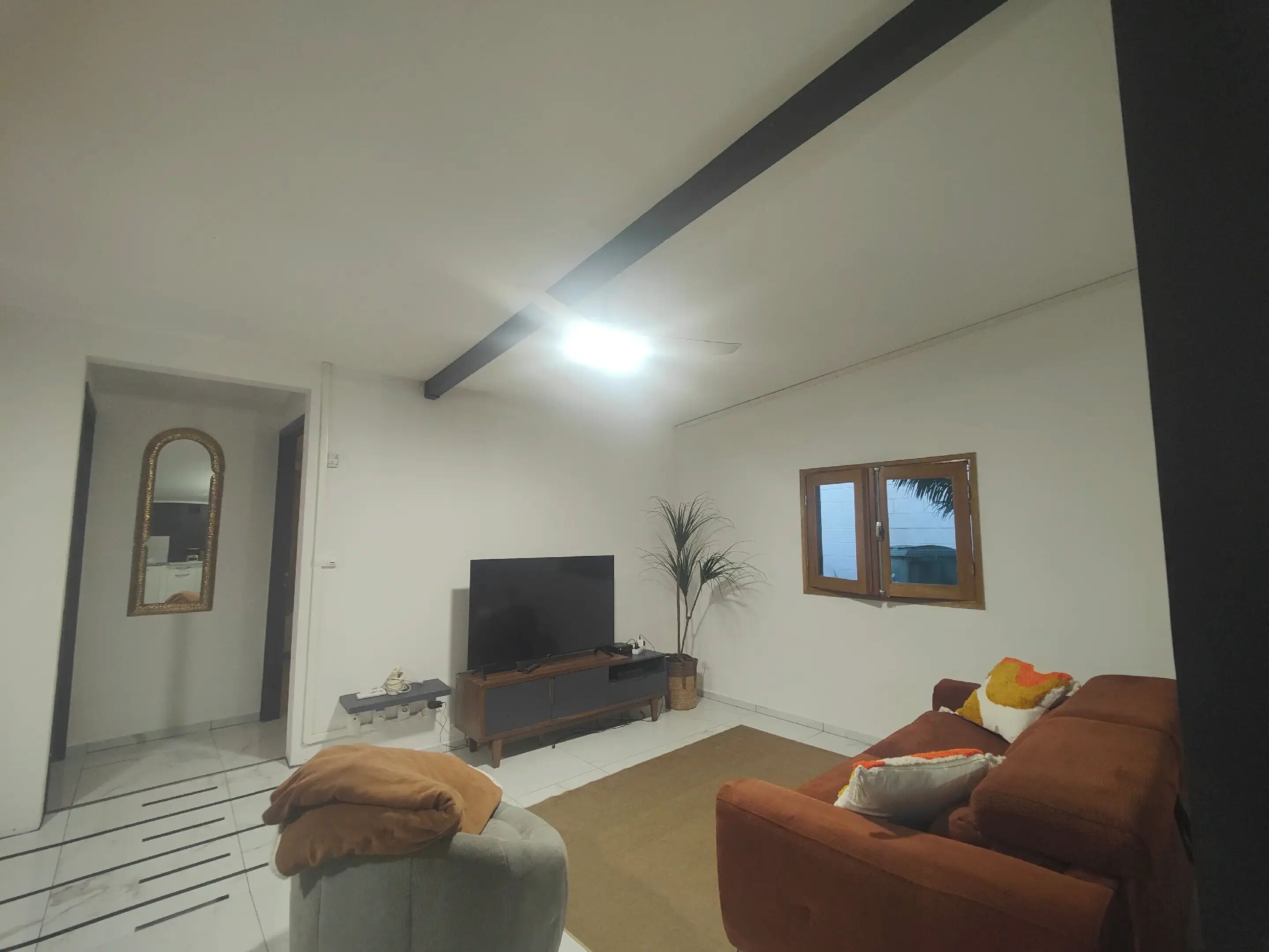 A living room with a sofa, a television, and a window.