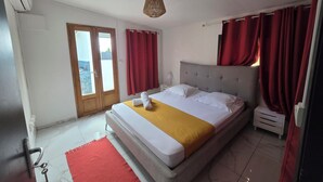 Een slaapkamer met een bed, een rood vloerkleed, een houten deur en een raam.