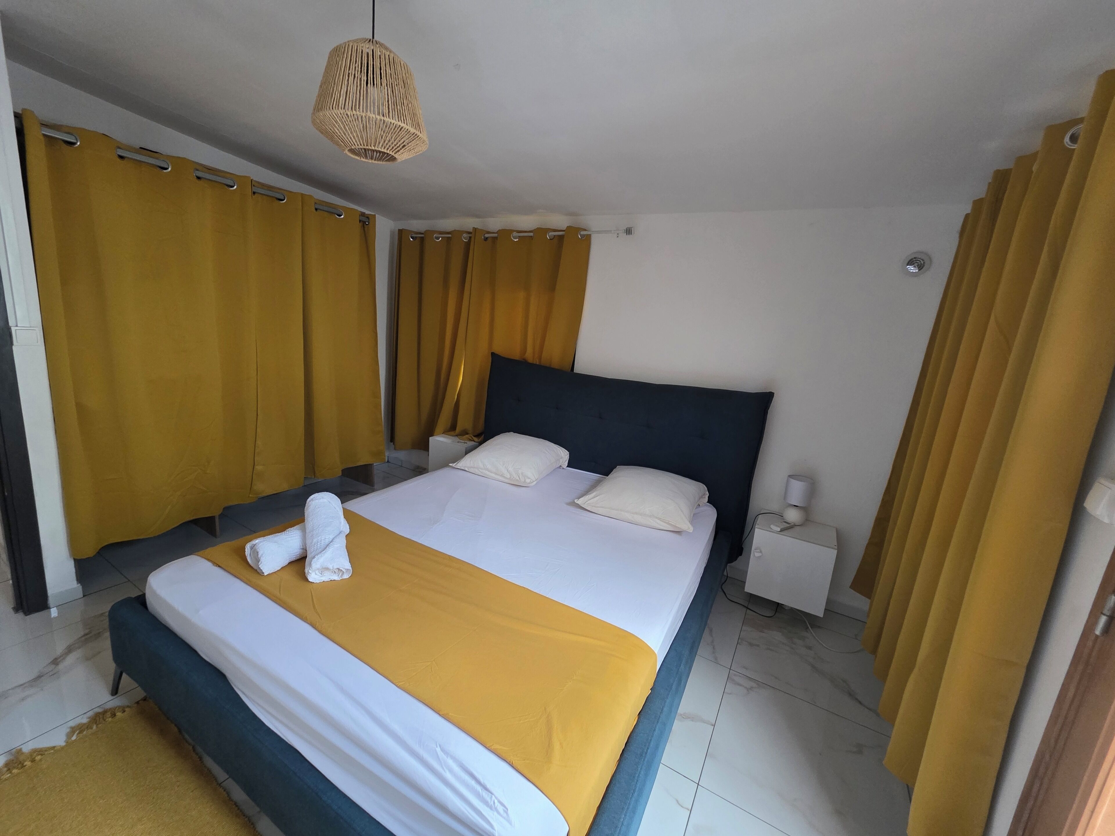 Une chambre d’hôtel avec un lit, une table de chevet, une lampe et des rideaux.