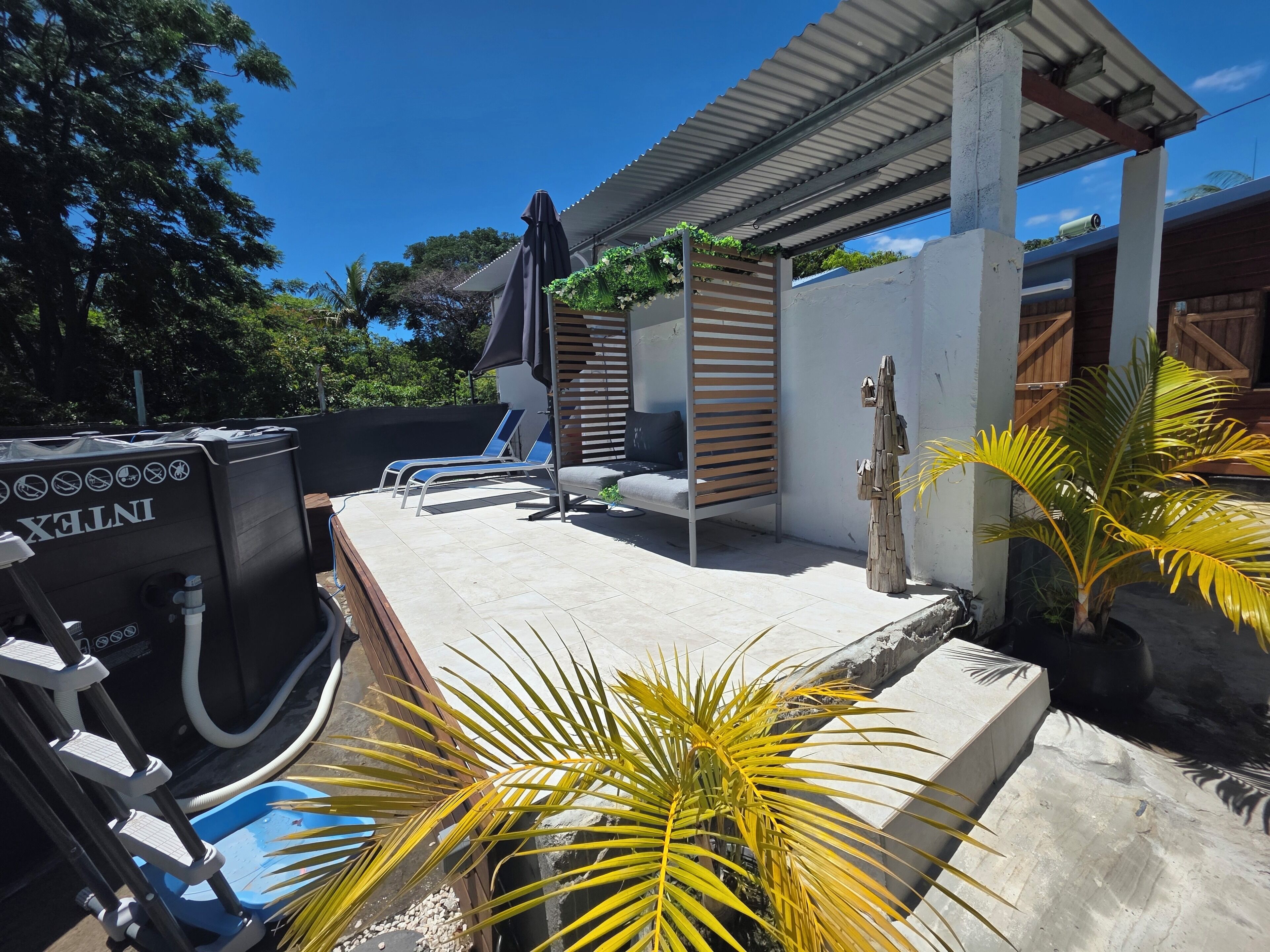 A pool area with lounge chairs, a water filtration system, and a pergola with a canopy.