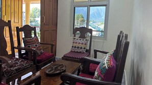 A room with wooden furniture, a dining table, and a window with a view of mountains. - Jan Mahal (Srinagar)