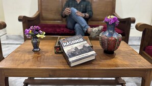 A wooden table with a book titled "Kashmir" and two vases with flowers. - Jan Mahal (Srinagar)