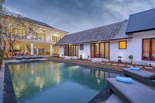 Une maison moderne dotée d’une piscine, d’un espace extérieur aménagé et d’un jardin bien entretenu.