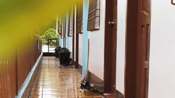 A corridor with patterned floor tiles, wooden doors, and a tiled ceiling.