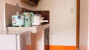 A compact kitchen with a refrigerator, a microwave, and a kettle on the counter.