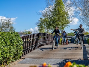 Un pont en bois doté de rampes en métal, entouré de verdure et de bâtiments résidentiels.