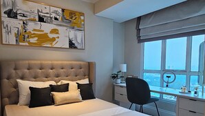 A modern bedroom with a large bed, a desk, and a view of the city. - Roseville SOHO and Suites by Nagisa Bali (South Tangerang)