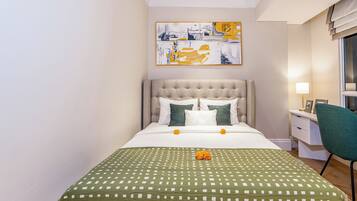 A neatly made bed with a green checkered bedspread, a tufted headboard, and two pillows.