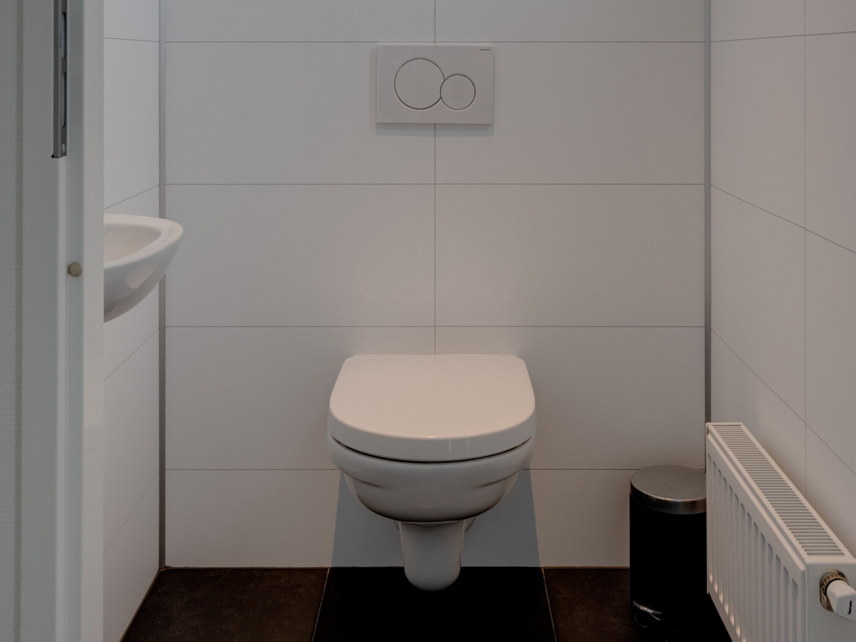 A small, modern bathroom with a toilet, a sink, and a radiator.
