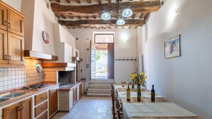 A kitchen with wooden cabinets, a tiled backsplash, and a dining area with a table set for two. - Country House in Marche with Pool & Views (Cagli)