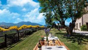 An outdoor dining area with a table set for two, a bottle of wine, and a view of mountains. - Country House in Marche with Pool & Views (Cagli)